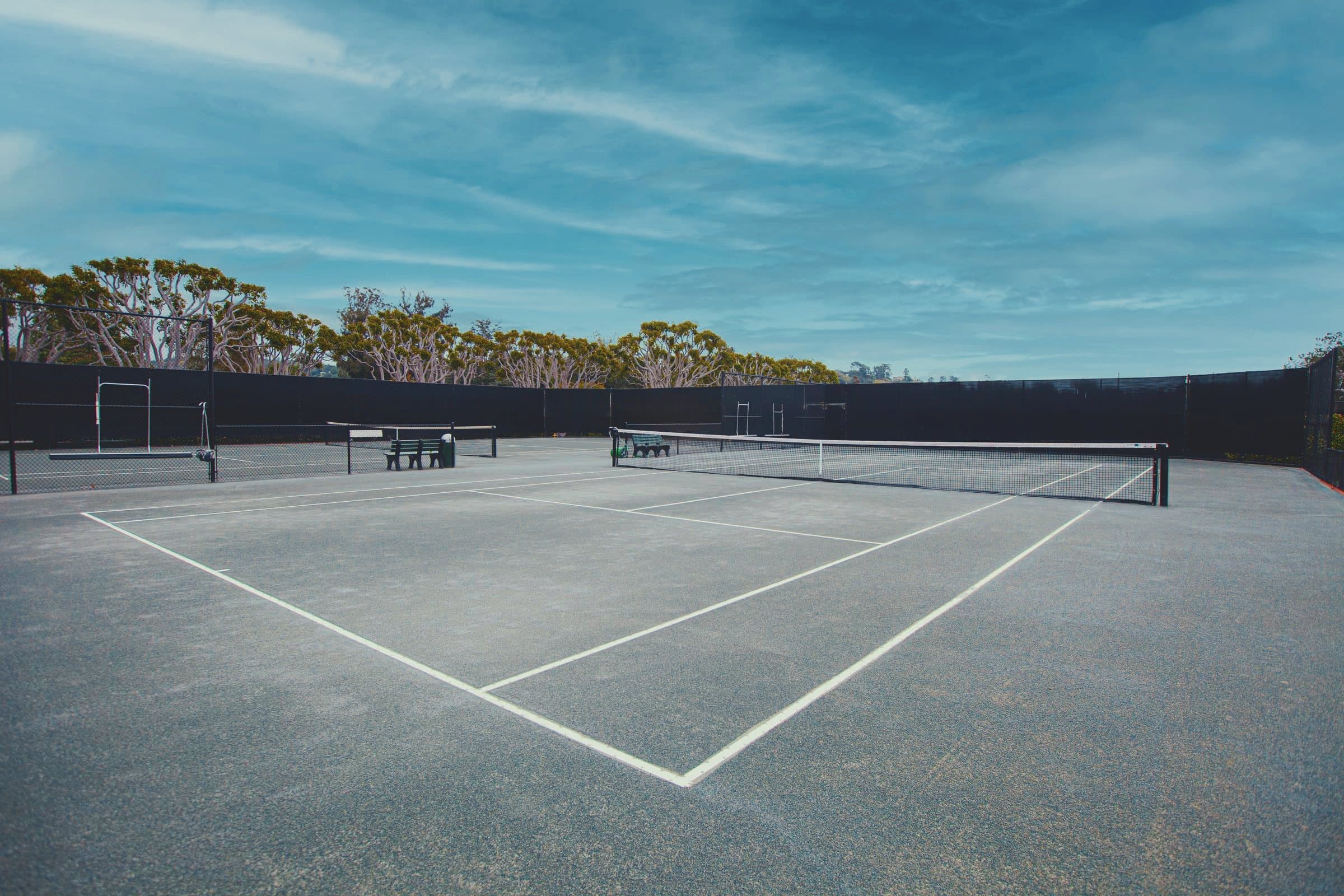 A clay court under a wide blue sky